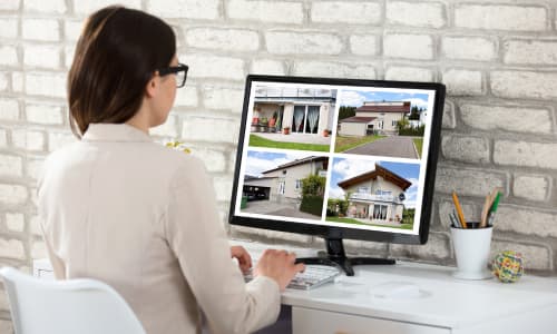 Woman viewing property listings on a computer screen, representing online estate agent marketing and property uploads on DoerUpper